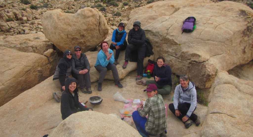 A group of veterans rest on a rocky landscape on an outward bound veterans course.